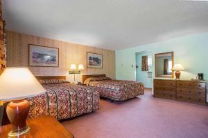 a hotel room with two beds and a table with a lamp at Rodeway Inn Lincoln I-93 in Lincoln