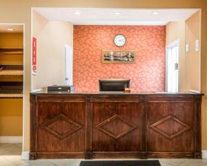 a reception desk with a clock on a wall at Econo Lodge Lakes Region in West Ossipee