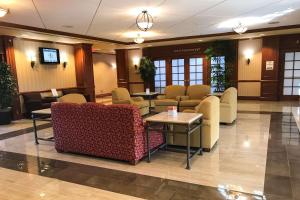 a waiting room with chairs and tables in a lobby at Clarion Hotel & Conference Center in Toms River
