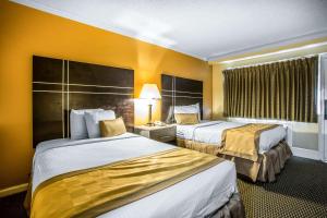 two beds in a hotel room with yellow walls at The Boards AC in Atlantic City