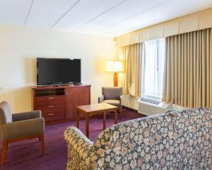 a hotel room with a couch and a flat screen tv at Clarion Hotel Somerset - New Brunswick in Somerset