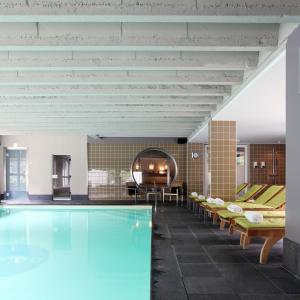 a pool in a room with chairs and a table at Hotel De Pits in Heusden - Zolder