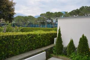 a hedge in front of a white building with trees at Apartment Locarno-Lido in Locarno