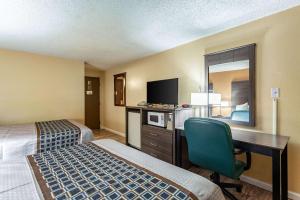 a hotel room with two beds and a desk with a television at Rodeway Inn in Farmington