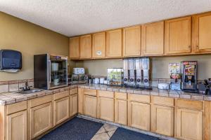 a large kitchen with wooden cabinets and a tv at Rodeway Inn in Farmington