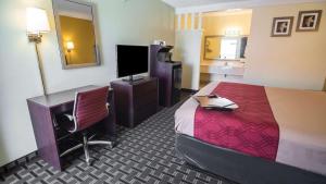 um quarto de hotel com uma cama, uma secretária e uma televisão em Econo Lodge Downtown Albuquerque em Albuquerque