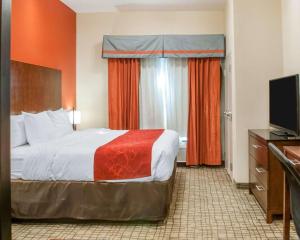 a hotel room with a bed and a flat screen tv at Comfort Suites in Roswell