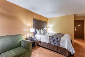 ein Hotelzimmer mit einem Bett und einem Stuhl in der Unterkunft Rodeway Inn in Farmington