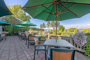a patio with tables and chairs with umbrellas at The Inn at Gran View Ogdensburg, Ascend Hotel Collection in Ogdensburg