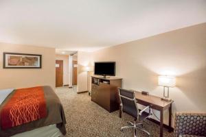 a hotel room with a bed and a desk and a television at Quality Inn in Corning