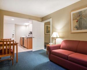 a living room with a red couch and a kitchen at Quality Inn Massena in Massena