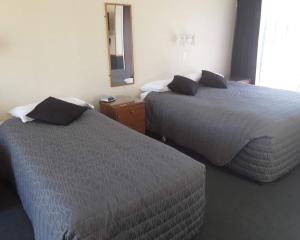 Habitación de hotel con 2 camas y espejo en Sundowner Motel, en Blenheim