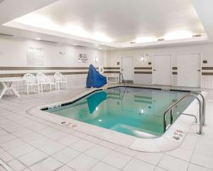 una piscina en una habitación con sillas y mesas en University Inn Vestal, en Vestal