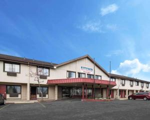 a building with a car parked in a parking lot at Rodeway Inn Syracuse Carrier Circle in East Syracuse