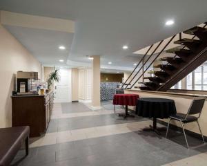 a lobby with a staircase and a table and chairs at Rodeway Inn Syracuse Carrier Circle in East Syracuse