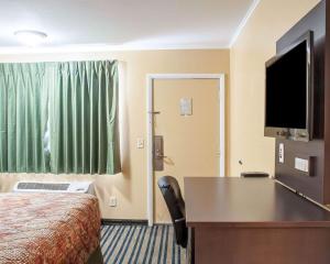 una camera d'albergo con letto, scrivania e TV di Amherst Inn & Suites ad Amherst