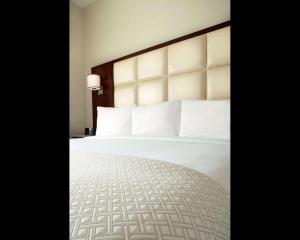 a hotel room with a bed with white sheets and pillows at Cambria Hotel New York - Chelsea in New York