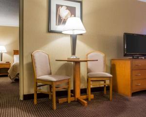 a hotel room with a table with two chairs and a lamp at Clarion Hotel & Suites Riverfront in Oswego