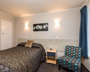 a hotel room with a bed and a chair at Comfort Inn Tayesta Motel in Invercargill