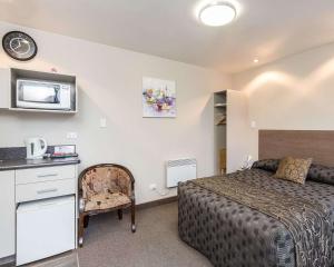 a hotel room with a bed and a microwave at Comfort Inn Tayesta Motel in Invercargill