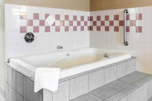 eine weiße Badewanne im gefliesten Bad in der Unterkunft Quality Inn in Defiance