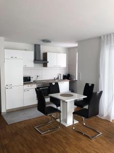 uma cozinha com armários brancos e uma mesa e cadeiras em Ferienwohungen Akwant em Baden-Baden