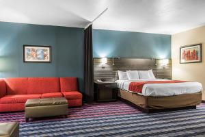 a hotel room with a bed and a red couch at Comfort Suites Fairgrounds West in Oklahoma City