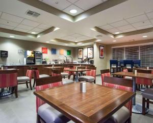 a restaurant with wooden tables and chairs and a cafeteria at Comfort Suites Central-I-44 in Tulsa