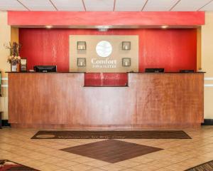 a reception desk in a lobby with a red wall at Comfort Inn & Suites in Elk City