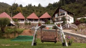 ein Haus mit einem Spielplatz vor einem Haus in der Unterkunft Hotel Cabañas El Rincón de las Campanas in Nobsa