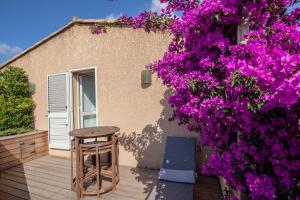 - un patio avec des fleurs violettes et une table dans l'établissement Résidence Guddelmoni, à Propriano