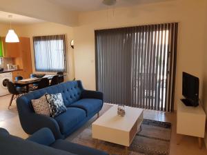 sala de estar con sofá azul y mesa en Sirena Sunrise, Apartment 4, en Pafos