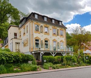 uma casa grande com uma varanda numa rua em Strandhotel Buckow gut-Hotels SEE em Buckow