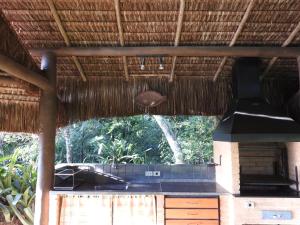 an outdoor kitchen in a straw hut with a stove at Sítio Rodamonte in Ilhabela