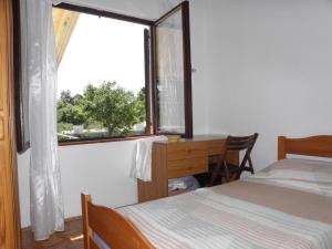 een slaapkamer met een bed, een bureau en een raam bij Apartments Kuce - 150m from the beach with parking in Sušica