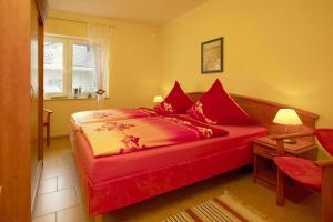 a red bed with red pillows in a bedroom at Haus Neptun in Ostseebad Karlshagen