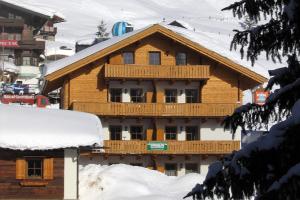 Casa de madera con balcón en la nieve en Ferienwohnungen LANG - Ski & Mountain Apartments, en Königsleiten