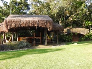 a hut with a grass roof on a yard at Sítio Rodamonte in Ilhabela