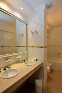 a bathroom with two sinks and a mirror and a toilet at Gran Hotel Skorpios in Mar del Plata