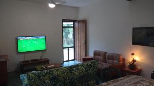a living room with a couch and a flat screen tv at Sítio Rodamonte in Ilhabela