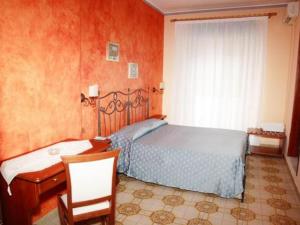 
a hotel room with a bed, chair, and nightstand at Costa Azzurra in Giardini Naxos
