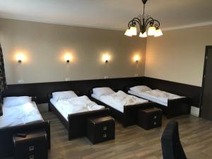 a room with three beds and a chandelier at Hotel Gościniec in Włocławek