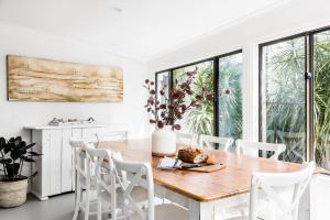 a dining room with a wooden table and white chairs at A PERFECT STAY - Beachwood in Byron Bay