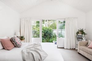 a white bedroom with a bed and a couch at A PERFECT STAY - Beachwood in Byron Bay