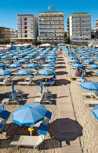 a bunch of blue umbrellas and chairs on a beach at Hotel Caravelle - Nuova Gestione 2026 in Cattolica