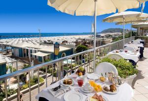 a table with food on a balcony next to the beach at Hotel Caravelle in Cattolica