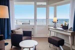 a living room with a desk and a view of the ocean at Hotel Neptun in Warnemünde