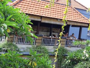 a house with people sitting on a balcony at Lotus Tirta Seminyak in Seminyak