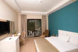 a bedroom with a bed and a television and a balcony at Green Bay Resort & Spa - All Inclusive in Guvercinlik