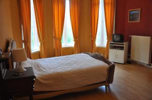 a bedroom with a bed and a tv and windows at Château De La Croix Bizet in Moulineaux
